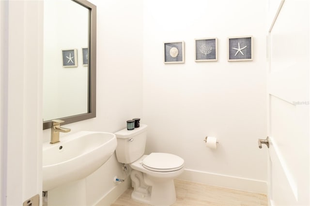 bathroom with toilet, sink, and hardwood / wood-style flooring