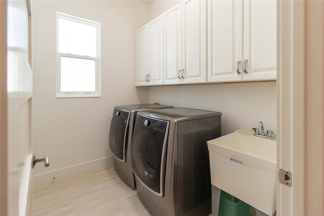 laundry area featuring separate washer and dryer, cabinets, and sink