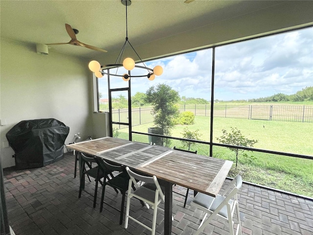 sunroom / solarium with ceiling fan with notable chandelier