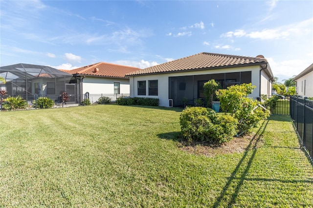 rear view of house with a lanai and a lawn