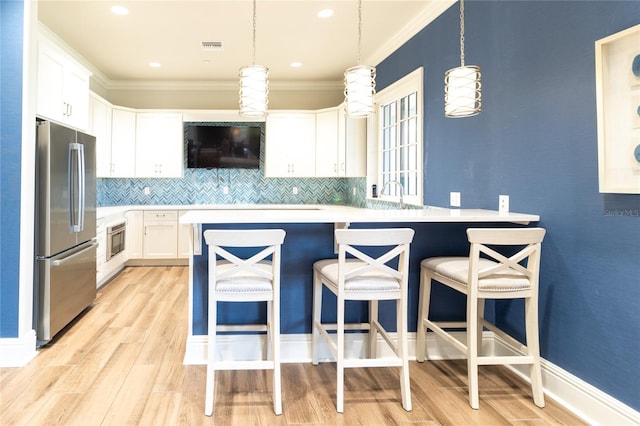 kitchen featuring backsplash, stainless steel appliances, white cabinetry, and light hardwood / wood-style flooring