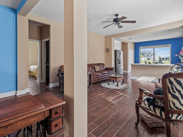 living room featuring ceiling fan, a textured ceiling, and dark wood-type flooring