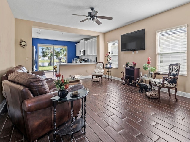 living room featuring a healthy amount of sunlight, ceiling fan, dark wood-type flooring, and a textured ceiling