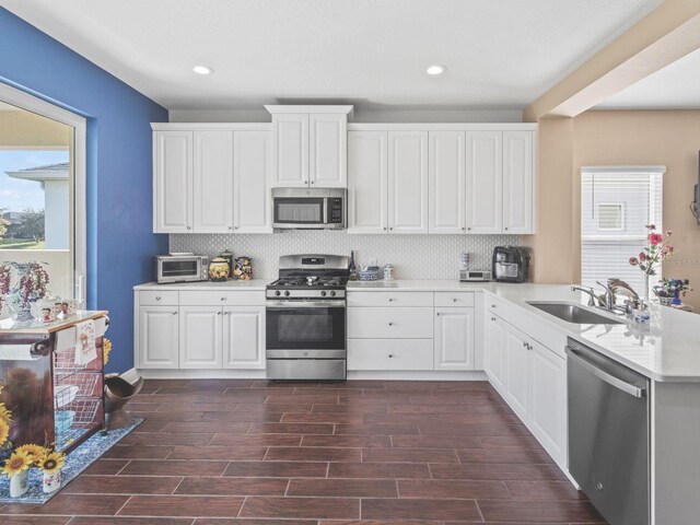 kitchen with dark wood-type flooring, white cabinetry, sink, and stainless steel appliances