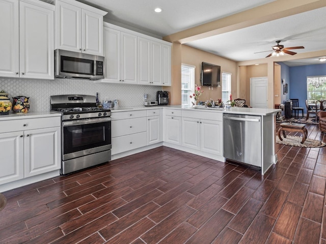 kitchen with kitchen peninsula, white cabinetry, stainless steel appliances, and dark hardwood / wood-style flooring