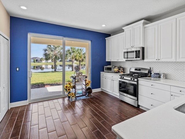 kitchen featuring white cabinets, stainless steel appliances, dark hardwood / wood-style flooring, and a water view