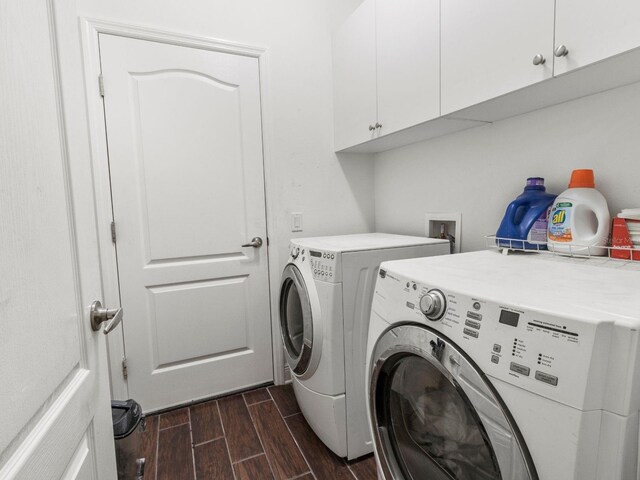 clothes washing area with separate washer and dryer, cabinets, and dark hardwood / wood-style flooring