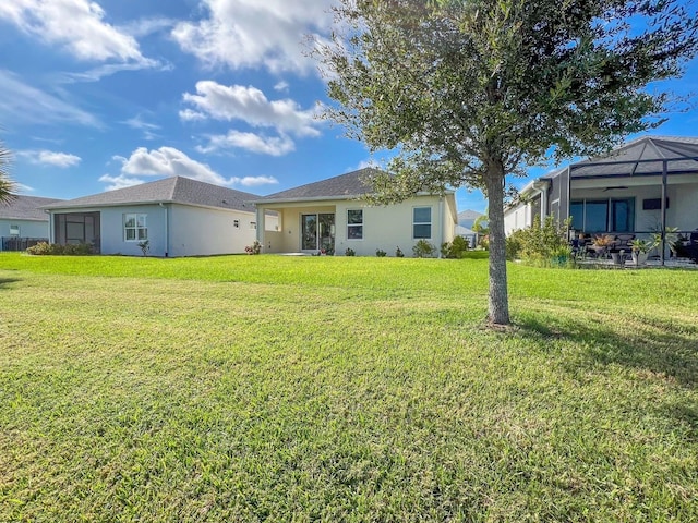 rear view of property with glass enclosure and a lawn