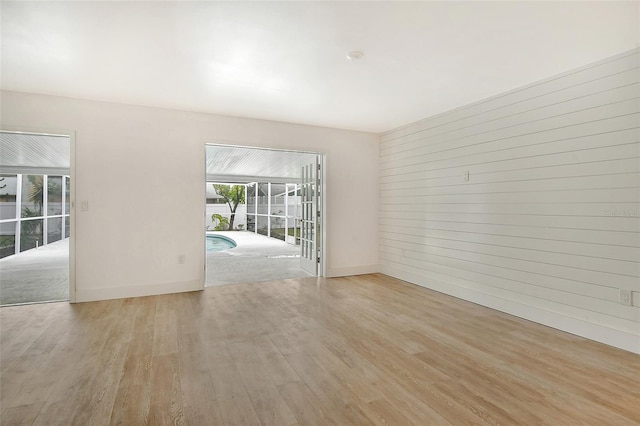 unfurnished room featuring light wood-type flooring and wood walls