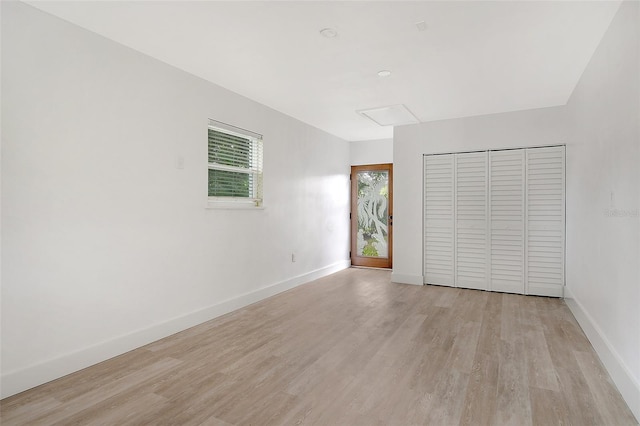 unfurnished bedroom with light wood finished floors, a closet, and baseboards