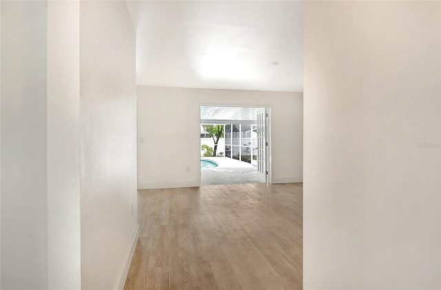 corridor with light wood-type flooring and baseboards