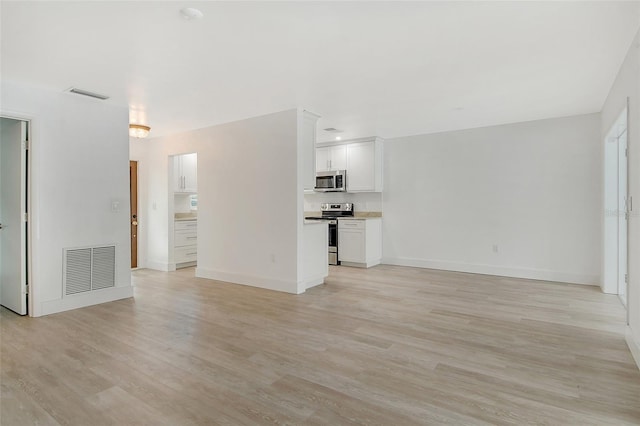 unfurnished living room featuring baseboards, visible vents, and light wood-type flooring