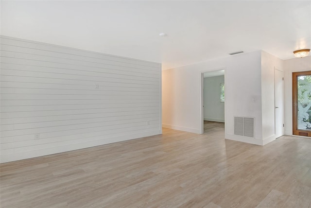 empty room with visible vents, a wealth of natural light, and light wood-type flooring