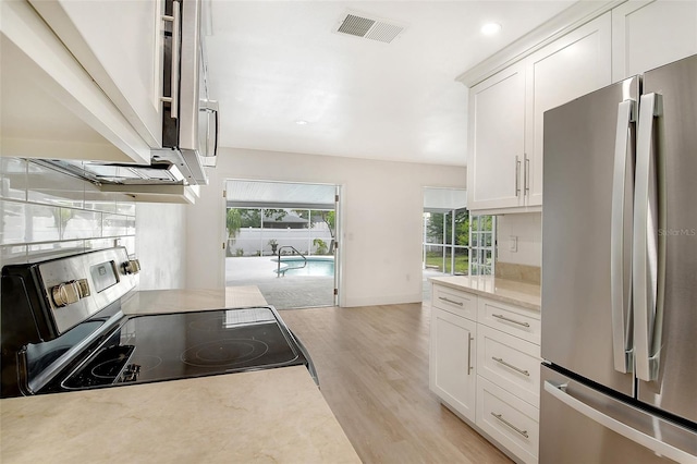 kitchen featuring light hardwood / wood-style floors, white cabinetry, light stone counters, and appliances with stainless steel finishes