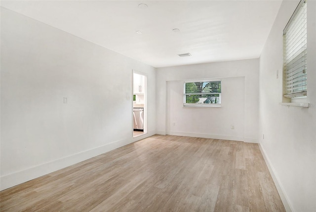 spare room featuring visible vents, light wood-style floors, and baseboards