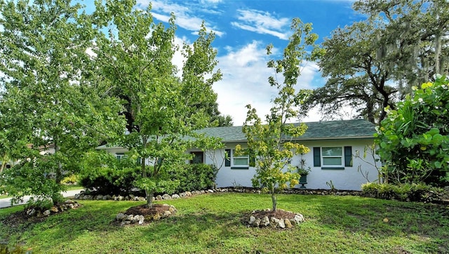 single story home featuring stucco siding, a shingled roof, and a front lawn