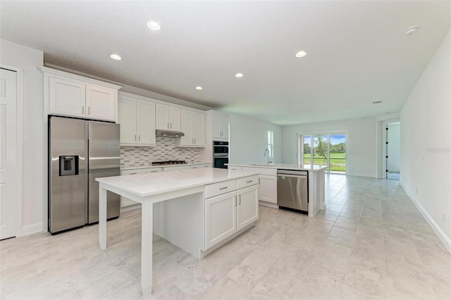 kitchen featuring white cabinetry, backsplash, stainless steel appliances, a center island, and sink