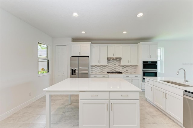 kitchen with white cabinets, a center island, stainless steel appliances, and sink