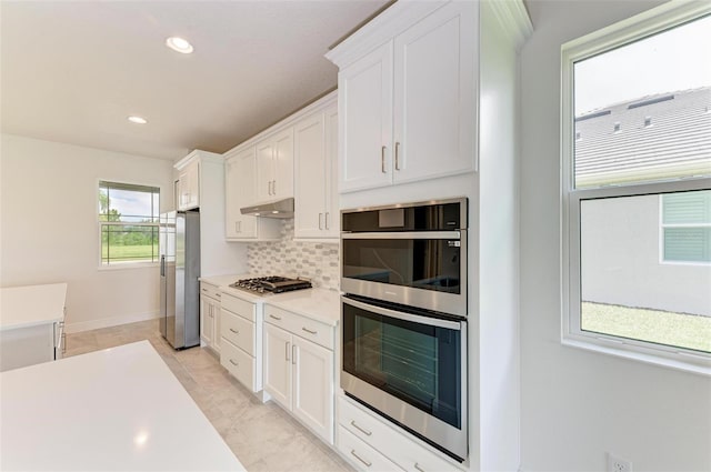 kitchen with stainless steel appliances, white cabinetry, and tasteful backsplash