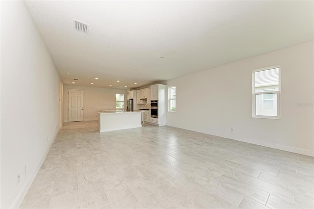 unfurnished living room featuring a healthy amount of sunlight and light tile patterned flooring