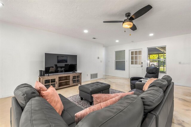 living room with a textured ceiling and ceiling fan