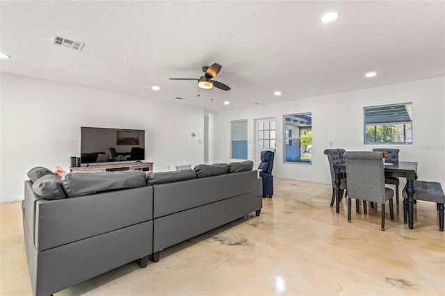 living room featuring ceiling fan and a textured ceiling