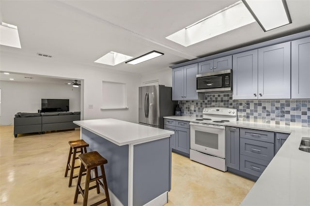 kitchen with a skylight, stainless steel appliances, a kitchen breakfast bar, ceiling fan, and a kitchen island