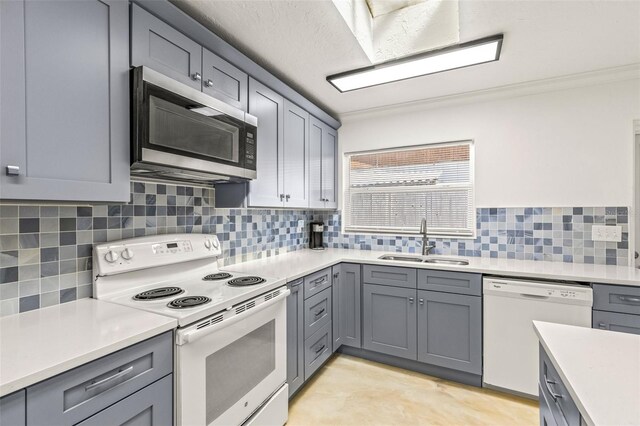 kitchen with white appliances, a skylight, sink, and decorative backsplash