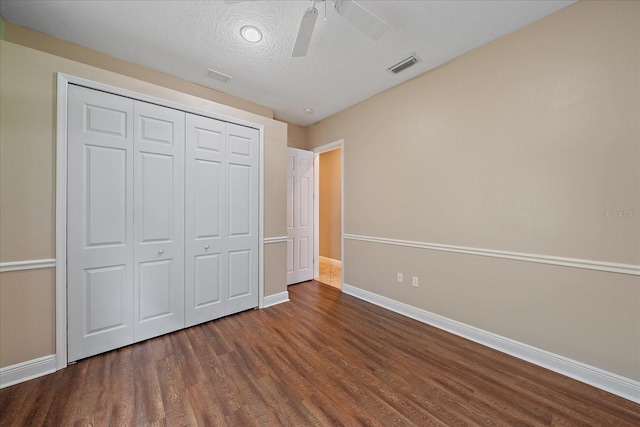 unfurnished bedroom with dark wood-type flooring, a textured ceiling, ceiling fan, and a closet