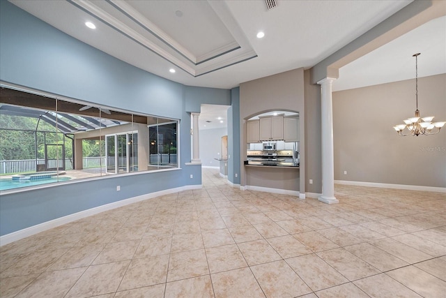 unfurnished living room featuring tile patterned flooring, an inviting chandelier, and ornate columns