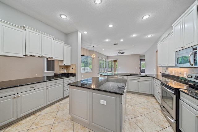 kitchen with a center island, stainless steel appliances, sink, kitchen peninsula, and ceiling fan