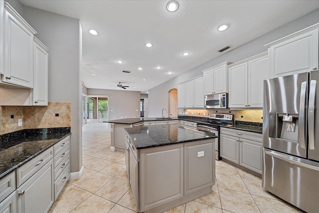 kitchen with stainless steel appliances, light tile patterned floors, a kitchen island, sink, and ceiling fan