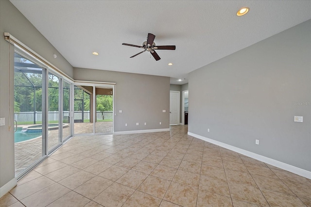 tiled empty room with ceiling fan and a textured ceiling