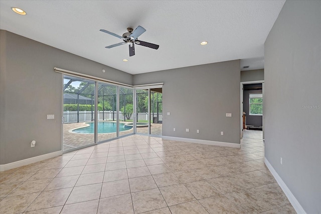 empty room featuring a wealth of natural light, ceiling fan, light tile patterned floors, and a textured ceiling