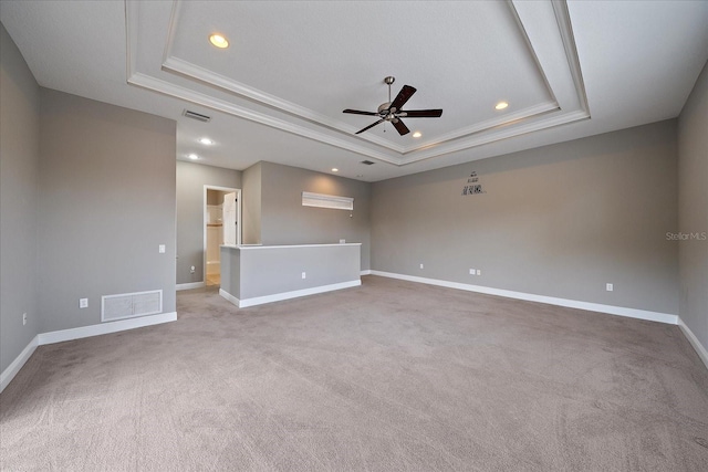 spare room featuring light colored carpet, ceiling fan, ornamental molding, and a tray ceiling