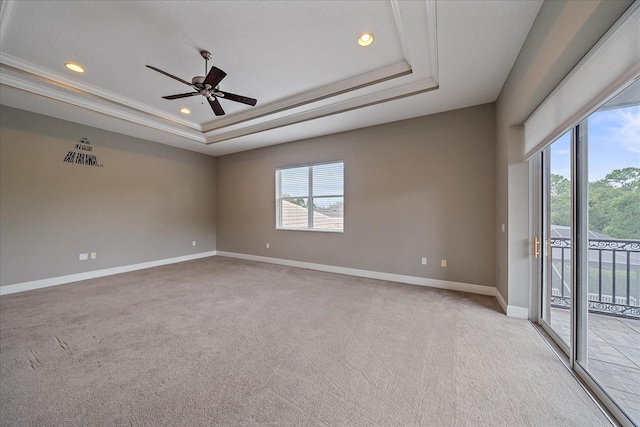 carpeted empty room featuring a tray ceiling, ornamental molding, ceiling fan, and a textured ceiling