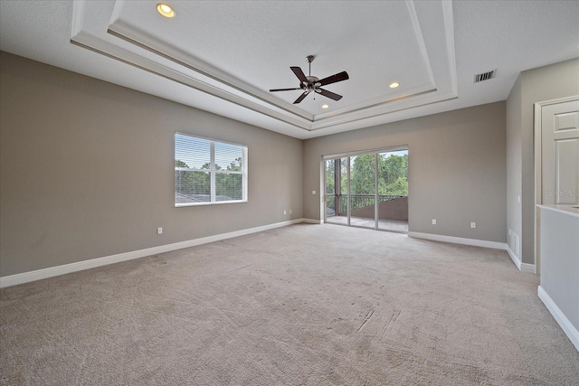 carpeted spare room with a tray ceiling, a textured ceiling, and ceiling fan