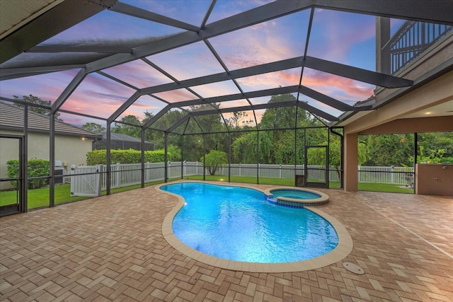 pool at dusk with an in ground hot tub, a patio, and a lanai