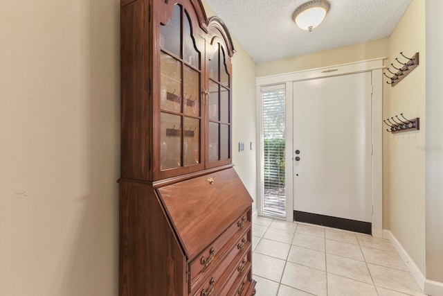 foyer entrance with a textured ceiling and light tile patterned floors