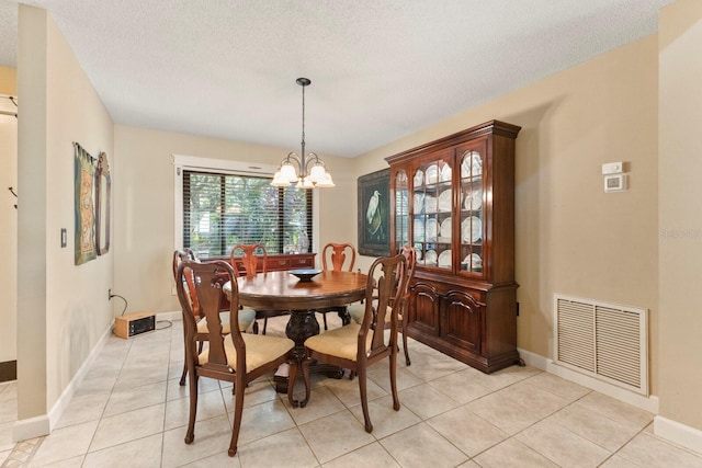 dining area with a textured ceiling, light tile patterned flooring, and a notable chandelier