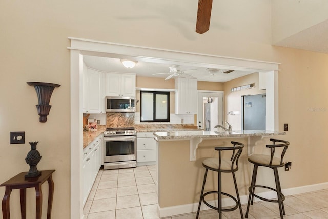 kitchen featuring ceiling fan, kitchen peninsula, stainless steel appliances, and white cabinetry