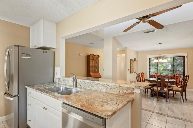 kitchen with ceiling fan with notable chandelier, pendant lighting, appliances with stainless steel finishes, sink, and white cabinetry