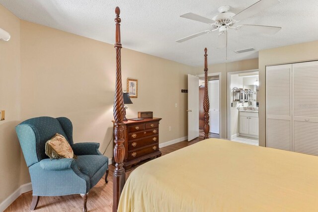 bedroom featuring hardwood / wood-style floors, a textured ceiling, ensuite bath, ceiling fan, and a closet