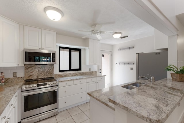 3601 Quail Hollow Ln, Bradenton, FL 34210 - kitchen featuring stainless steel appliances, decorative backsplash, light stone countertops, white cabinetry, and a peninsula