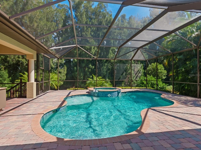 view of pool featuring an in ground hot tub, glass enclosure, and a patio area