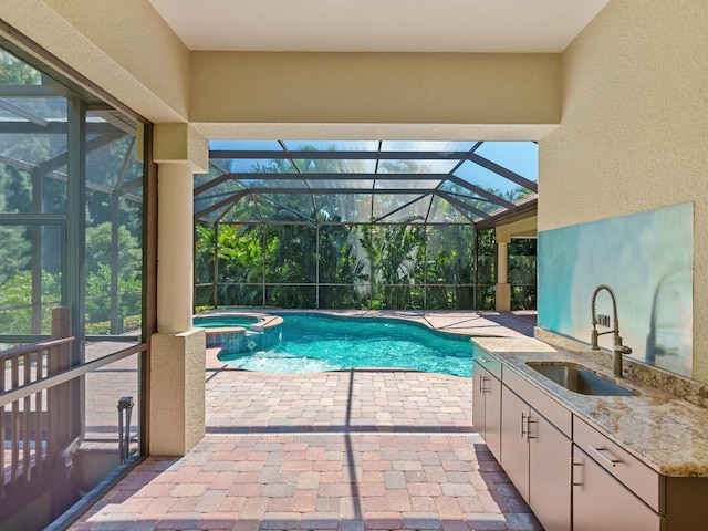 view of swimming pool featuring an in ground hot tub, a patio, a lanai, and sink