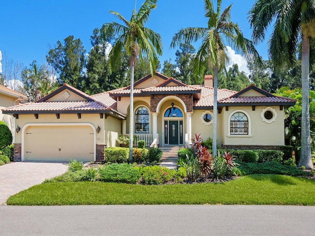 mediterranean / spanish home with a front yard, a porch, and a garage