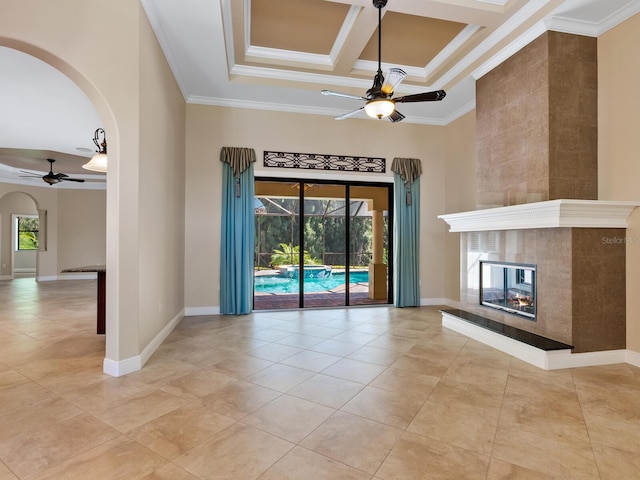 unfurnished living room with ornamental molding, coffered ceiling, ceiling fan, a high ceiling, and a tiled fireplace