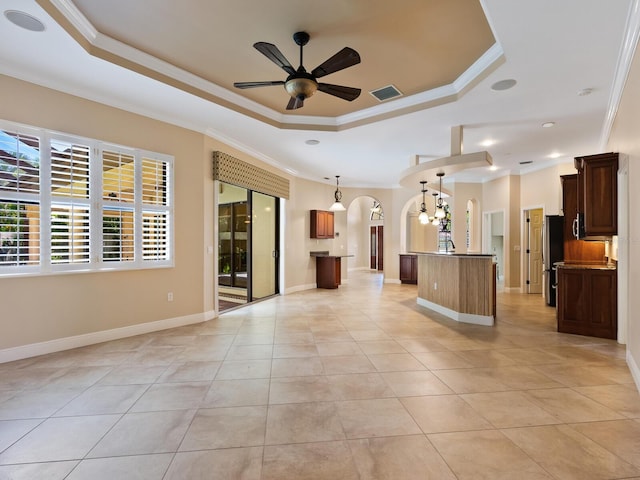 unfurnished living room featuring light tile patterned floors, a tray ceiling, ceiling fan, and crown molding