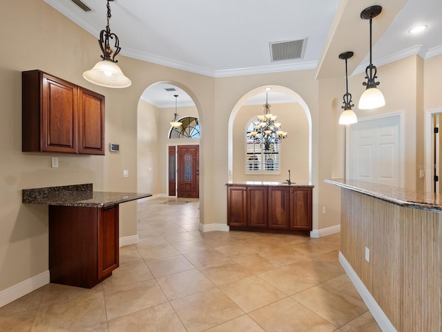 kitchen with crown molding, a chandelier, pendant lighting, dark stone counters, and light tile patterned floors